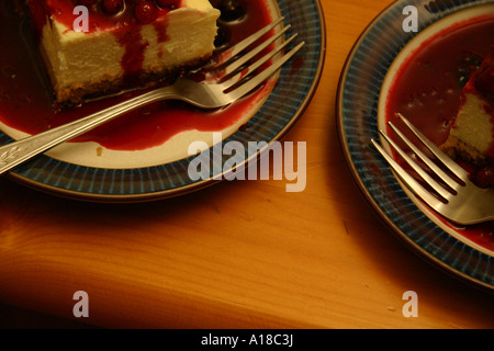 Deux plaques de desserts, gâteau au fromage avec coulis de framboises et de fruits, sont assis côte à côte avec deux fourches d'argent. Banque D'Images