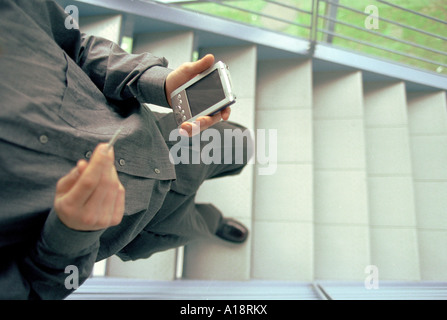 L'homme à smart casual vêtements walking down steps tenant un ordinateur de poche Banque D'Images