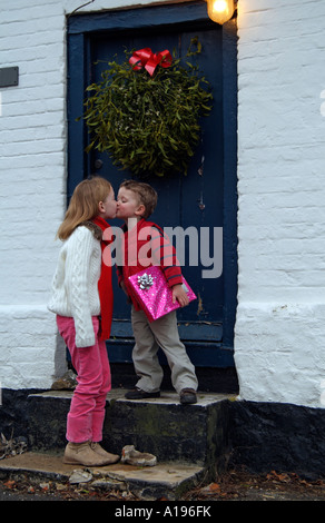 Enfants baisers sous le gui.Ancienne porte avec affichage gui.Temps de Noël Banque D'Images