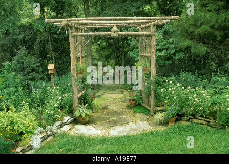 Chalet jardin avec chemin dallé par cèdre rustique arbor archway menant au jardin d'ombre et faite à la main birdboxes qui fleurit en été, USA Banque D'Images