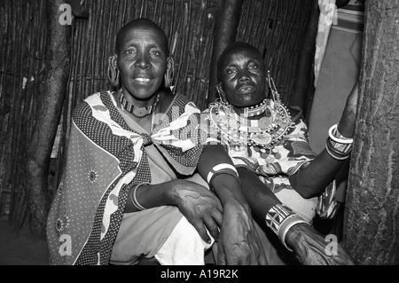 Portrait en noir et blanc de deux sœurs Maasai en robe traditionnelle et bijoux assis dans leur maison faite à partir de méteries traditionnelles. Kajiado, Kenya Banque D'Images