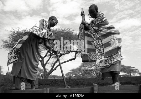 B/W de Maasai femmes dans la construction traditionnelle de robe a envahi la terre, logement plus durable dans leur communauté. Kajiado, Kenya Banque D'Images