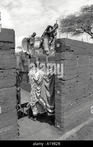 B/W de Maasai femmes dans la construction traditionnelle de robe a envahi la terre, logement plus durable dans leur communauté. Kajiado, Kenya Banque D'Images