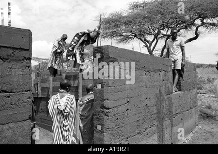 B/W de Maasai femmes dans la construction traditionnelle de robe a envahi la terre, logement plus durable dans leur communauté. Kajiado, Kenya Banque D'Images