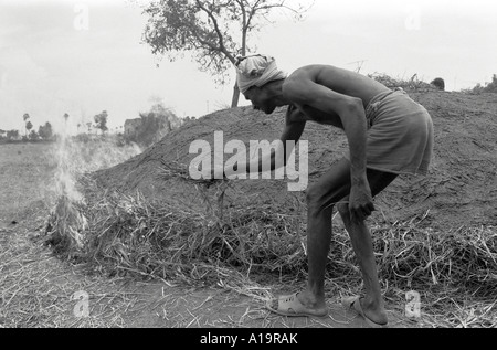 B/W d'un poterie éclairant un four primitif et traditionnel dans la campagne tamoul Nadu, en Inde du Sud Banque D'Images