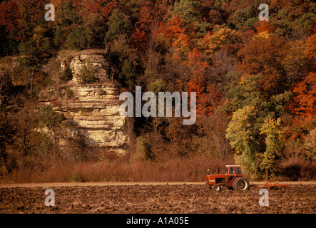 Vieux temps nostalgie : l'agriculteur sur le tracteur rouge champ de labour par Missouri River bluffs avec feuillage automne Midwest USA Banque D'Images
