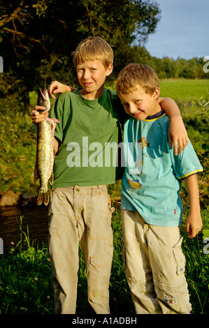 Les garçons, neuf et onze ans, sont maintenant un poisson qu'ils ont pêché le brochet Banque D'Images