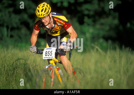 USA Washington Seattle Mountain bike rider races à travers les hautes herbes, à Des Moines Creek Park près de Sea Tac Airport Banque D'Images