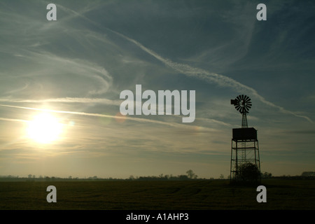 Moulin à vent élicté dans un champ silhoueté par le soleil couchant Banque D'Images