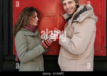 Couple dans des vêtements d'hiver avec les boissons chaudes Banque D'Images