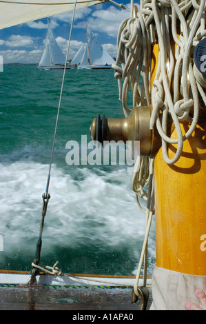 Un treuil laiton et conduites d'crampons sur le mât d'un voilier classique d'une course contre deux autres bateaux disponibles Banque D'Images