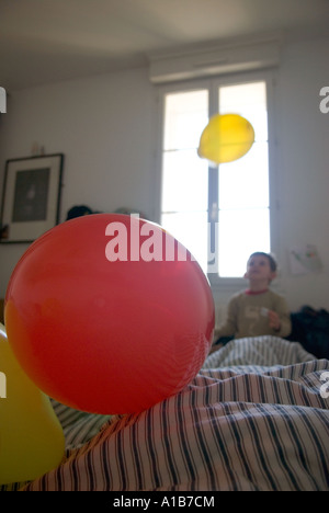 Une chambre avec scène jeune garçon en arrière-plan à jouer avec ballon en face d'une fenêtre lumineuse Banque D'Images