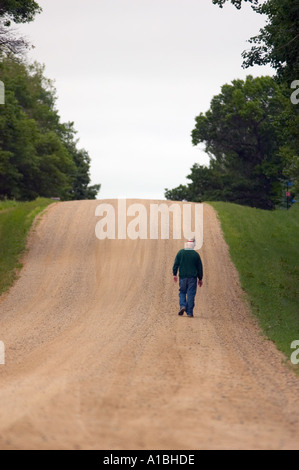 Lone man walking down de gravier avec pente Minnesota rural Banque D'Images