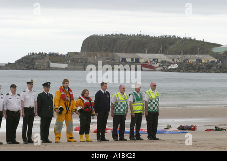 Les paramédics de la RNLI personnel de garde-côtes avec port de Portrush derrière sur West Strand pendant minutes de silence pour commémorer la Journée D Banque D'Images