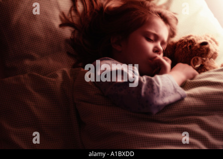 Au lit enfant nounours câlins sucer les doigts Banque D'Images