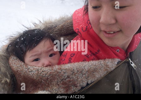 Jeune fille Inupiat avec sa nièce emmitouflé sur son dos Kaktovik île Barter Arctic National Wildlife Refuge en Alaska Banque D'Images