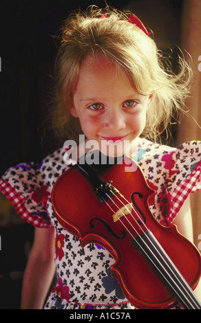 Petite fille avec son violon expression grave montre son intérêt sincère pour apprendre quelque chose de complexe ou difficile Banque D'Images