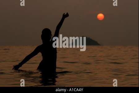 Silhouette d'une jeune femme dansant dans la mer au coucher du soleil, de la Thaïlande, Koh Chang Banque D'Images