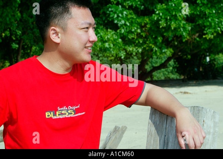 Jeune homme donne sur la mer de la plage de Pulau Pangkor Island Malaisie Banque D'Images