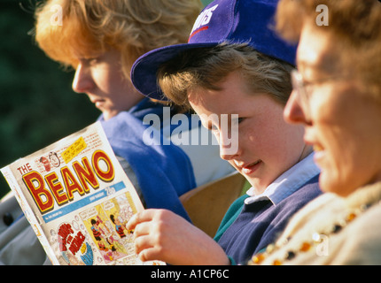 Jeune garçon LA LECTURE DES BANDES DESSINÉES AVEC LA MÈRE ET GRAND MÈRE UK Banque D'Images