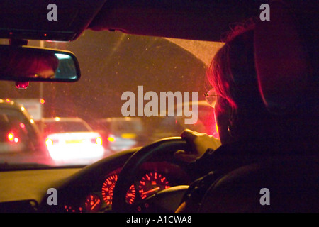 Woman driving car la nuit dans un embouteillage sur le M25 Banque D'Images