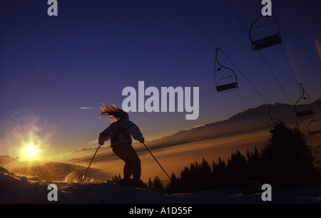 Le dernier skieur fille piste du jour au coucher du soleil Banque D'Images