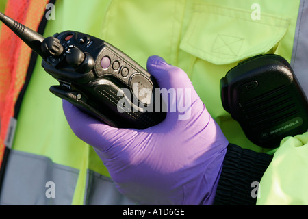 Une EMT dans une veste jaune tenant une radio Banque D'Images