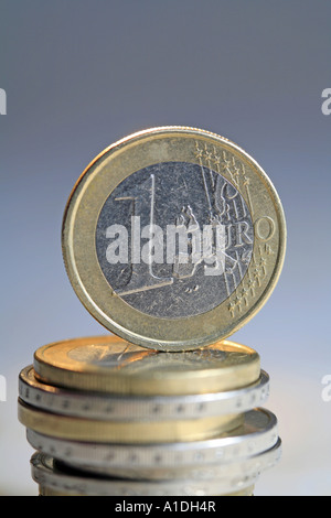 Une pièce en euro est debout jusqu'à une pile de pièces en euros Banque D'Images