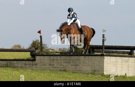 Jeune femme monte un cheval baie dans un concours complet Gloucestershire Royaume Uni Banque D'Images