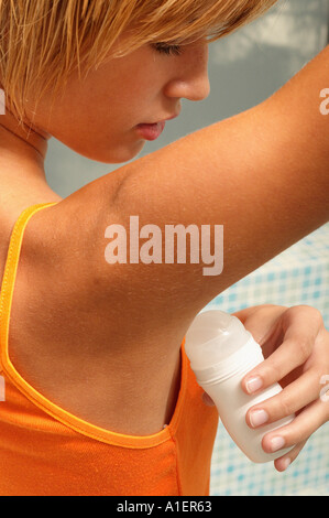 Young woman applying deodorant Banque D'Images