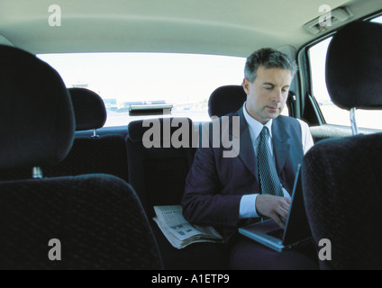 Businessman using laptop in backseat of car Banque D'Images