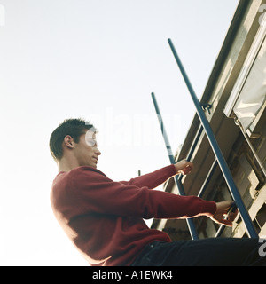 Man climbing ladder Banque D'Images