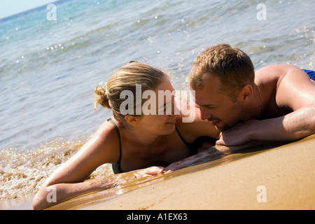 Couple couché dans le sable sur une plage grecque Banque D'Images
