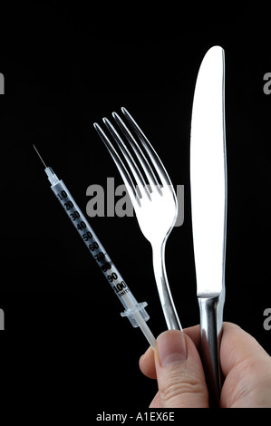Main tenant une seringue fourchette et couteau Banque D'Images