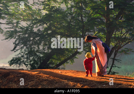 Femme portant un sari indien et la marche à pied avec son petit enfant le long d'un chemin de terre Banque D'Images