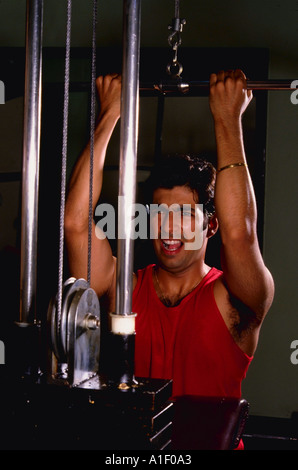 L'homme indien avec look d'effort lors de l'utilisation d'appareil Nautilus pour lever des poids Banque D'Images