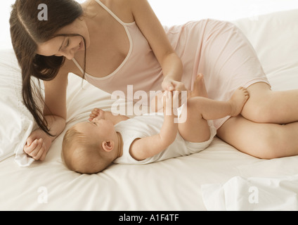 Le bébé et la mère sur le lit, se tenant la main Banque D'Images