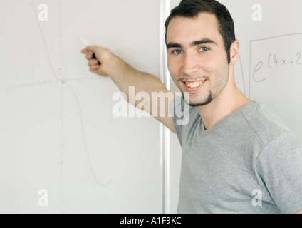 Jeune homme écrit sur le tableau blanc Banque D'Images