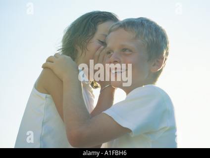 Girl whispering to boy Banque D'Images