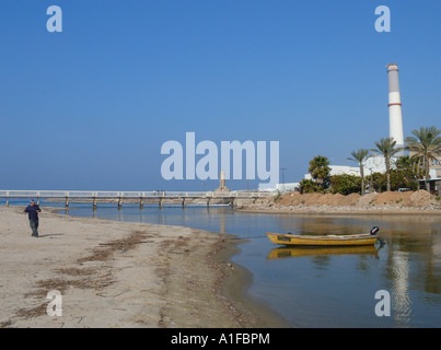 Un homme tirant un bateau en bois à côté de la centrale électrique de la lecture à l'estuaire du fleuve yarqon yarkon ou dans le nord de Tel Aviv, Israël Banque D'Images