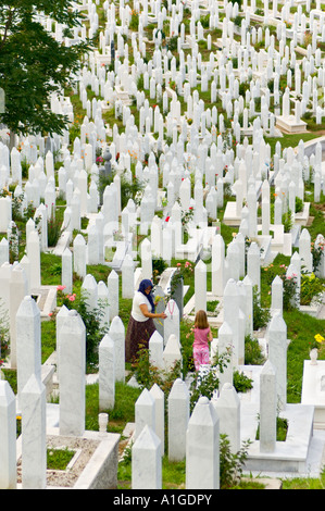 Une femme musulmane et un enfant ont tendance une tombe dans un cimetière de guerre Sarajevo Bosnie-Herzégovine Banque D'Images