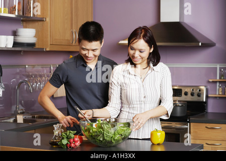 Young man standing looking at a young woman preparing food Banque D'Images
