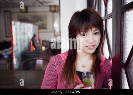 Portrait d'une jeune femme tenant un verre de boisson à base de plantes Banque D'Images