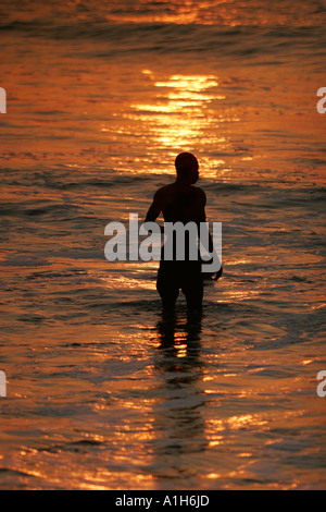 Baignade dans l'homme au coucher du soleil de l'océan plage Boboi Lodge, près de Kartong Gambie Banque D'Images