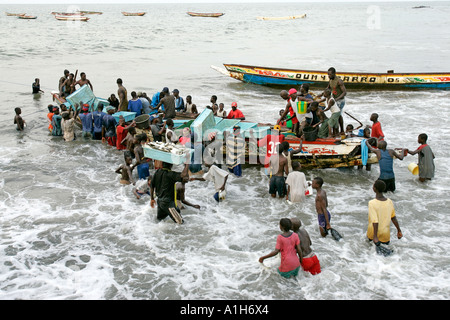 Les jeunes hommes wade en surf bateau de pêche de la Gambie Bakau Banque D'Images