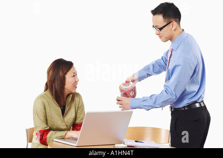 Portrait of a businessman pouring tea dans un verre en face d'une businesswoman Banque D'Images