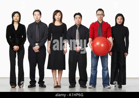 Portrait d'un jeune homme debout tenant une balle avec un groupe de cadres d'entreprise Banque D'Images