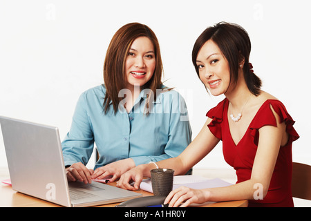 Portrait of two businesswomen assis devant un ordinateur portable Banque D'Images