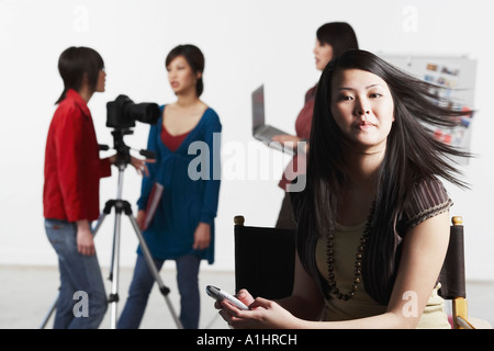 Portrait of a young woman holding a mobile phone avec ses amis debout derrière elle Banque D'Images