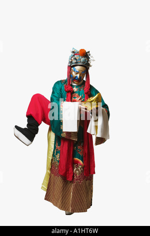 L'opéra chinois interprète masculin debout sur une jambe tenait un bol plein de pièces d'or Banque D'Images